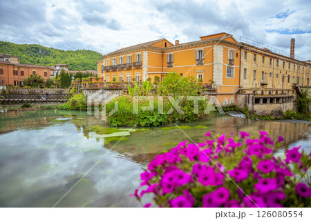Isola del Liri's picturesque riverfront with historic buildings and vibrant flowers.. 126080554