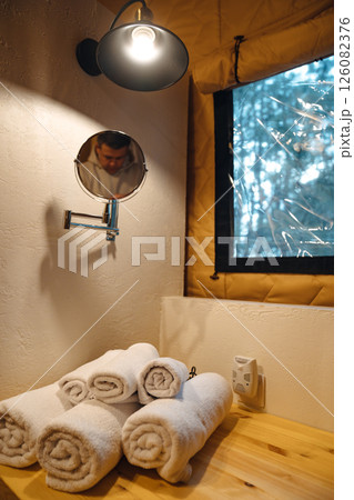 Lamp and round mirror in the bathroom in the tent house in the glamping. Lamp and round mirror in the bathroom in the tent house in the glamping. 126082376