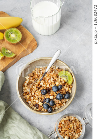 Homemade baked granola or muesli in a bowl with kiwi and blueberries on a light background Homemade baked granola or muesli in a bowl with kiwi and blueberries on a light background 126082472
