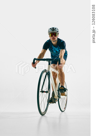 Full-length front view image of young man in full gear, cyclist in helmet and goggle riding bicycle isolated on white background. Full-length front view image of young man in full gear, cyclist in helmet and goggle riding bicycle isolated on white background. 126083108