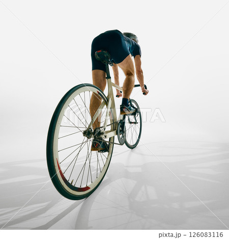 Back view of man, cyclist in motion, training, riding bicycle with determination and focus isolated on white background. Back view of man, cyclist in motion, training, riding bicycle with determination and focus isolated on white background. 126083116