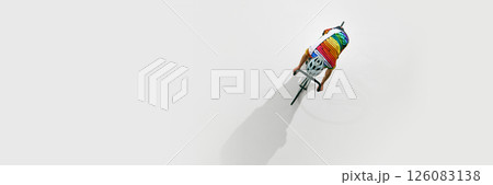 Aerial view of male cyclist in colorful uniform and helmet, in motion on bicycle, riding isolated on white background. Aerial view of male cyclist in colorful uniform and helmet, in motion on bicycle, riding isolated on white background. 126083138