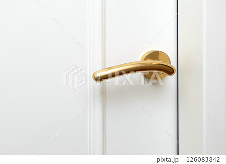 Golden door handle on a white door representing elegance and style Golden door handle on a white door representing elegance and style 126083842