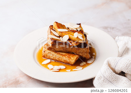 French toast with caramelized banana, syrup and almonds. 126084201