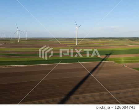 Agricultural tractor is working on the field with wind turbines. Aerial view 126084743