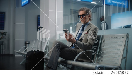 Airport Terminal: Mature Businessman with Suitcase Using Smartphone 126085077