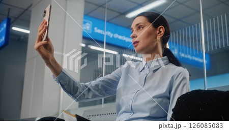Businesswoman Talking to Business Partner on Smartphone by Video Call, Waiting for Airplane Flight 126085083