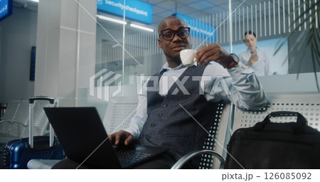 Airport Terminal: Businessman Using Laptop, Drinking Coffee, Smiling and Looking at Camera 126085092