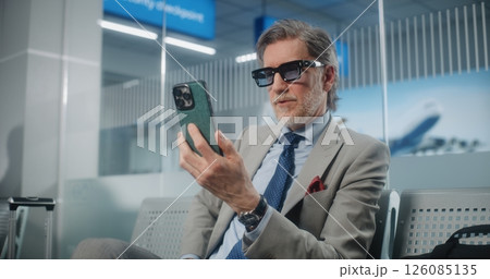 Airport Terminal: Entrepreneur Talking to Investor on Smartphone by Video Chat, Drinking Coffee 126085135
