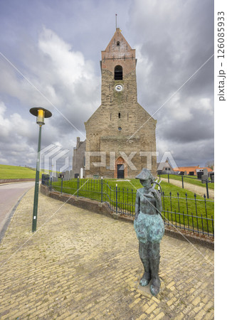Statue of a boy holding a fish in front of Wierum church in Friesland, Netherlands 126085933