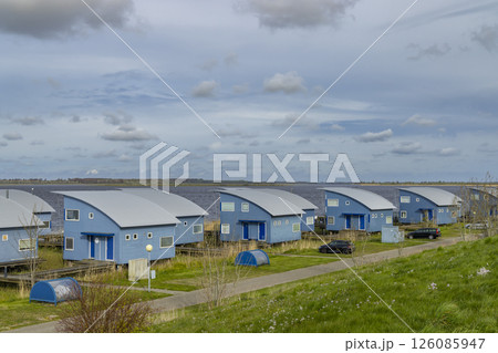 Blue vacation houses standing in a row by the lake on a cloudy day 126085947