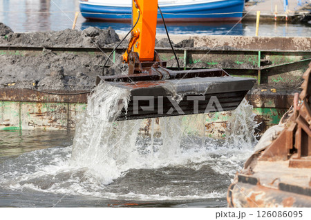 Excavator shovel digging in sand from water 126086095