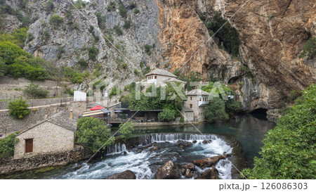 Blagaj Tekke monastery with Buna river near Mostar town in Bosnia and Herzegovina, Europe. Picturesque village nestled at the base of towering cliffs, river flowing through historic buildings. 126086303