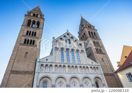 Cathedral in Pecs town in Hungary, Europe. Magnificent church facade featuring symmetrical towers and intricate architectural details against a clear blue sky. Cathedral in Pecs town in Hungary, Europe. Magnificent church facade featuring symmetrical towers and intricate architectural details against a clear blue sky. 126086310