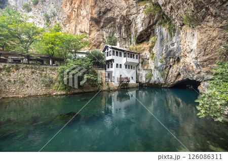 Blagaj Tekke monastery with Buna river near Mostar town in Bosnia and Herzegovina, Europe. Riverside House by Cliffside: A scenic view of a house nestled beside a cliff, overlooking a tranquil river. 126086311
