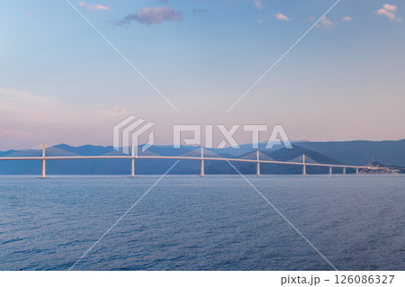 The Peljesac Bridge to Peljesac peninsula in Croatia, Europe. Scenic bridge stretches across the calm water, connecting distant shores under a serene sky during the tranquil hours of the day. 126086327