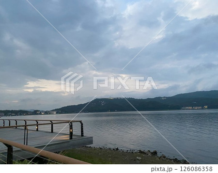 夕暮れ時の湖畔の遊歩道、対岸には灯りが点る山並み 夕暮れ時の湖畔の遊歩道、対岸には灯りが点る山並み 126086358