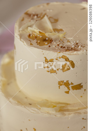 Delicious two tiered cake with gold leaf and white chocolate decorations 126086398