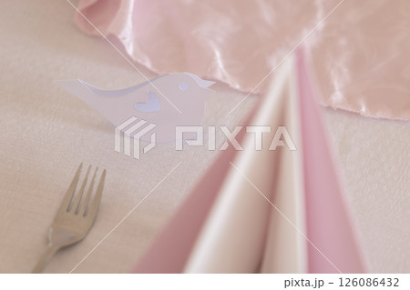 Wedding table setting with bird shaped placeholder and pink napkins 126086432