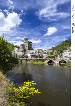 Estaing Castle and Bridge Reflecting on the Lot River in Aveyron, France, under a Cloudy Blue Sky Estaing Castle and Bridge Reflecting on the Lot River in Aveyron, France, under a Cloudy Blue Sky 126086588