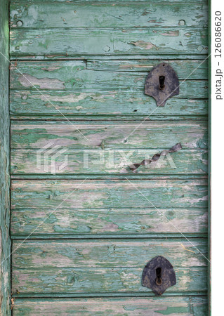 Weathered green wooden door with rusty metal hinges and handle in Wildendurnbach, Austria Weathered green wooden door with rusty metal hinges and handle in Wildendurnbach, Austria 126086620