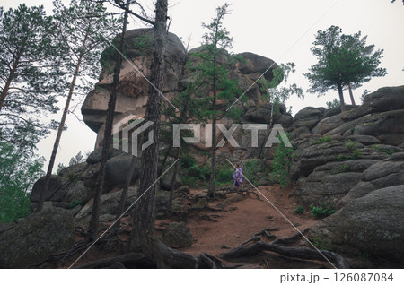 Man in Raincoat Exploring Rocky Forest Landscape 126087084