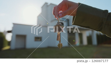 Key ring with keychain house in hand on background of house. Real estate concept for buying a new home. Key ring with keychain house in hand on background of house. Real estate concept for buying a new home. 126087177