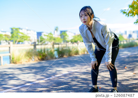 走って息切れする　息が切れる　川沿いをジョギングするかっこいい女性　 126087487