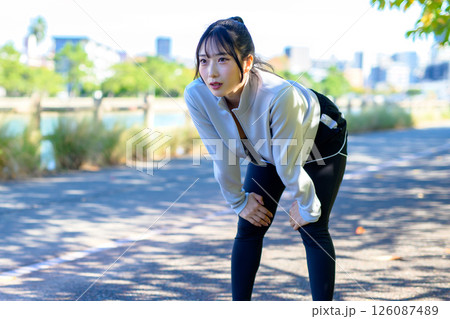 走って息切れする　息が切れる　川沿いをジョギングするかっこいい女性　トリミングアップ 126087489