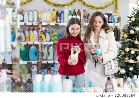 Girl with mother scanning barcodes on shampoo in festive store Girl with mother scanning barcodes on shampoo in festive store 126088164