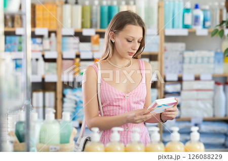 Woman in summer dress choosing pills in pharmacy Woman in summer dress choosing pills in pharmacy 126088229