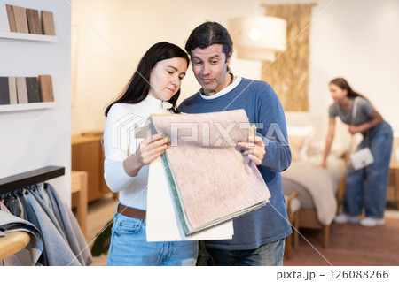Couple discussing collection of fabrics for furniture in apartment in furniture salon 126088266