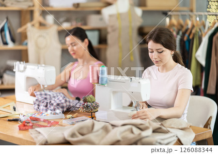 Two women tailor sews clothes in sewing machine Two women tailor sews clothes in sewing machine 126088344