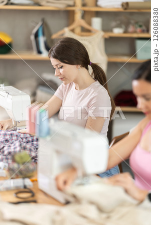 Two women tailor sews clothes in sewing machine Two women tailor sews clothes in sewing machine 126088380