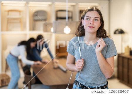 Young woman choosing decoration in furniture salon Young woman choosing decoration in furniture salon 126088407