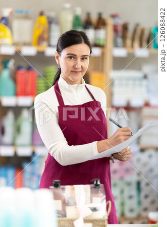 saleswoman writes down on paper the amount of the remaining goods in the warehouse 126088422