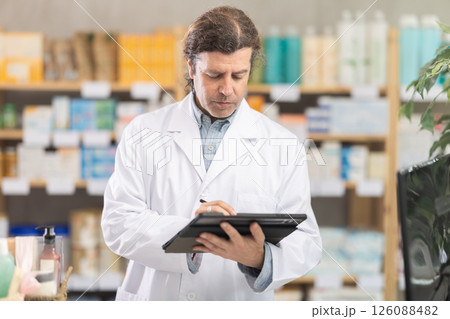Man pharmacist makes restock, uses electronic carrier tablet of information Man pharmacist makes restock, uses electronic carrier tablet of information 126088482