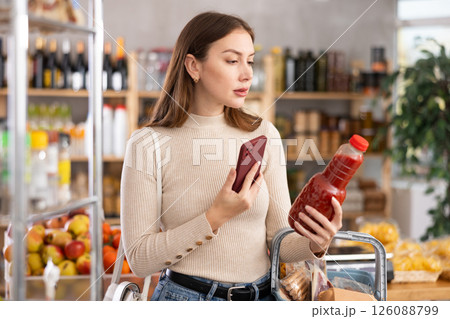 Girl customer holds bottle of tomato juice in hand, scans QR code on product label Girl customer holds bottle of tomato juice in hand, scans QR code on product label 126088799