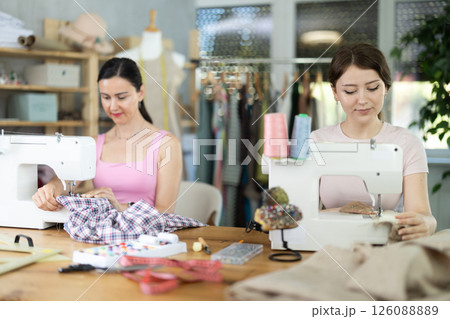 Two women tailor sews clothes in sewing machine 126088889