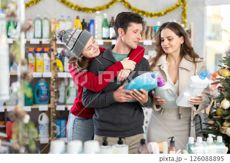 Couple man and woman with daughter choosing detergent in decorated store Couple man and woman with daughter choosing detergent in decorated store 126088895