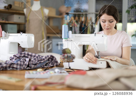 Woman seamstress sews on sewing machine in workshop 126088936