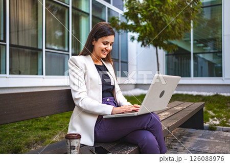Businesswoman working on laptop outdoors Businesswoman working on laptop outdoors 126088976