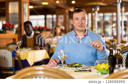 Positive adult businessman resting and having dinner in restaurant 126088999
