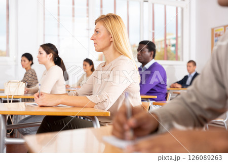 Interested adult woman sitting on lesson in school auditorium 126089263
