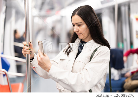 Woman in metro carriage points phone camera at an information board 126089276