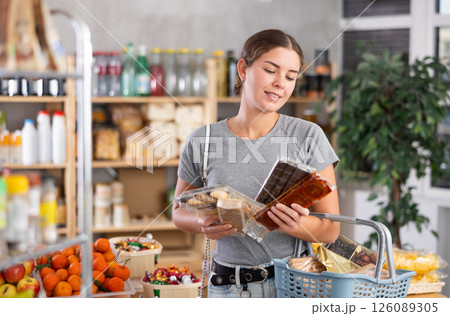 Grocery shopping at supermarket - girl chooses sweets, nougat, cookies and candies 126089305