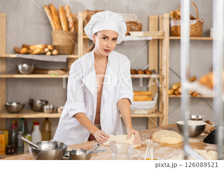 Seductive female chef kneading dough in rustic bakery 126089521
