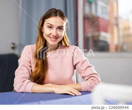Portrait of a positive and confident young woman sitting at a table Portrait of a positive and confident young woman sitting at a table 126089544