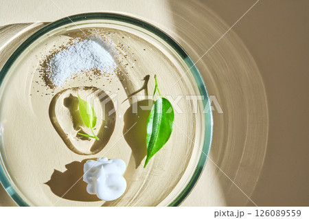 The texture of facial serum, cream and enzyme powder in a petri dish on a beige background. 126089559