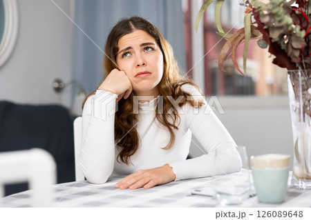 Upset woman sitting at table at home 126089648